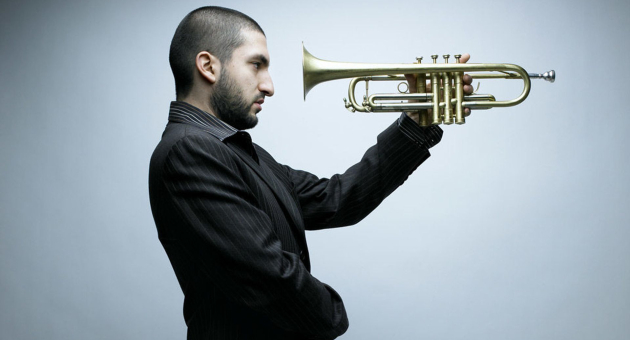 Ibrahim Maalouf in pak houdt trompet horizontaal voor zijn gezicht.