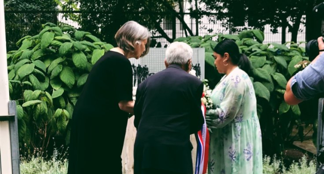 Bezoekers leggen zonnebloemen bij een maquette van het Indisch Monument tijdens een herdenkingsavond