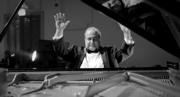 Zwart- wit afbeelding van pianist met zijn armen omhoog achter een piano