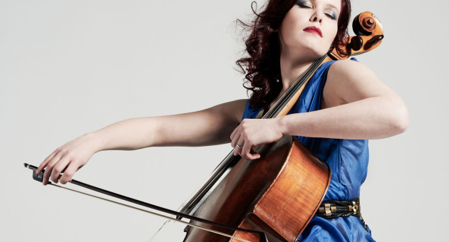 Maya Fridman in blauwe jurk die met haar ogen dicht cello speelt