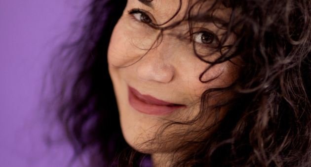 Vrouw met krullend haar lacht naar de camera.