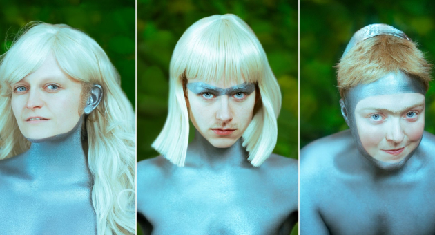 Drieluik van drie personen met metallic zilver geschminkte huid, futuristische pruiken en accessoires, poserend tegen een groene achtergrond.