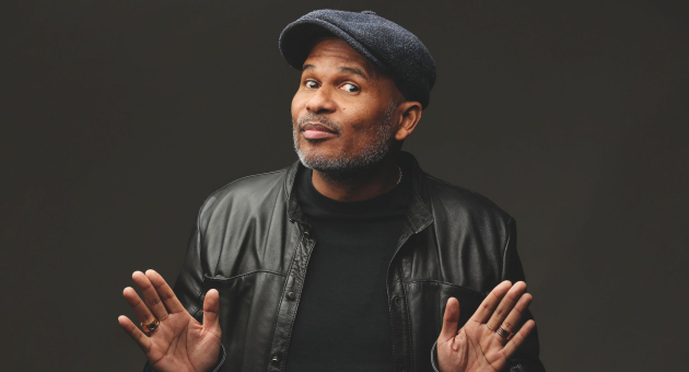 Roué Verveer voor een zwarte achtergrond in een zwarte leren jas, trui en pet