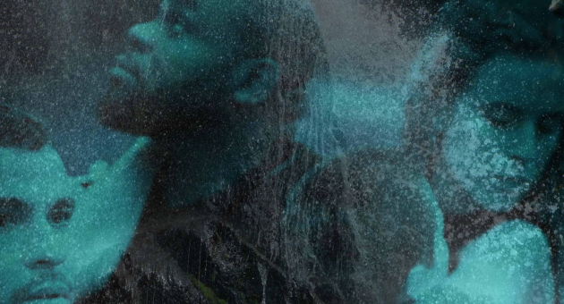 Drie mensen kijken ernstig in verschillende richtingen, bedekt met een blauwe nevel of mist.