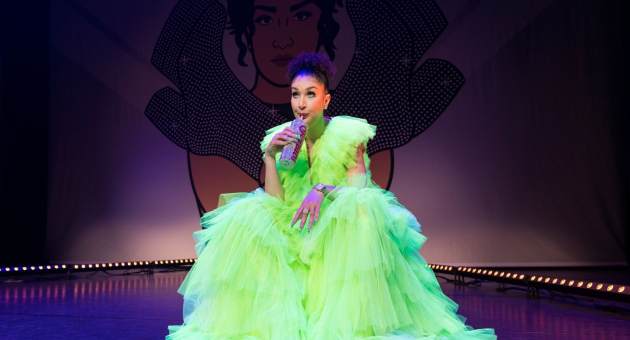 Soundos in neongele jurk drinkend uit beker. 