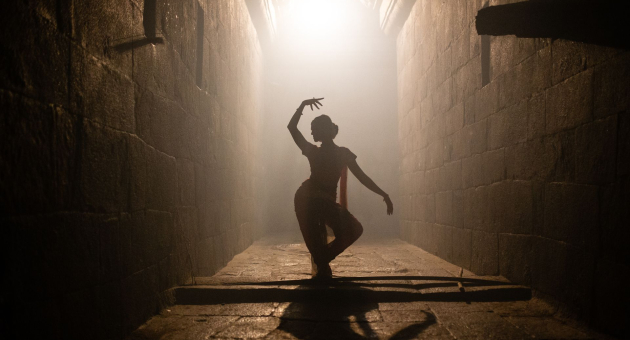 Danseres in ruimte in een moderne pose met lichtinval vanaf achter.