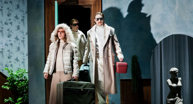 Drie reizigers met koffers in theatrale setting