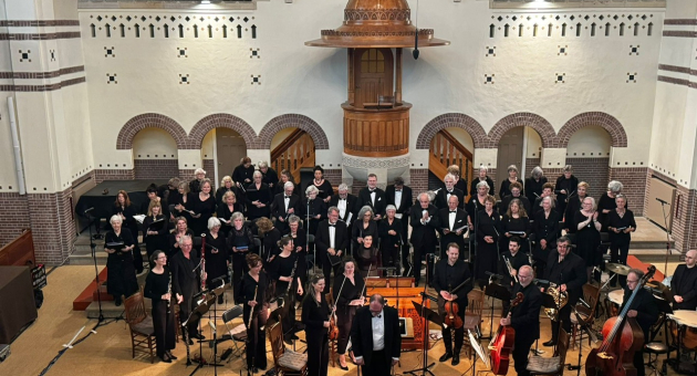Orkest in concertopstelling met dirigent vooraan in een kerkzaal