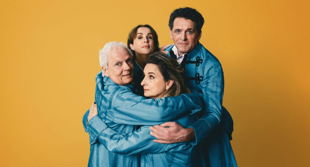 Vier acteurs in blauwe kostuums omarmen elkaar