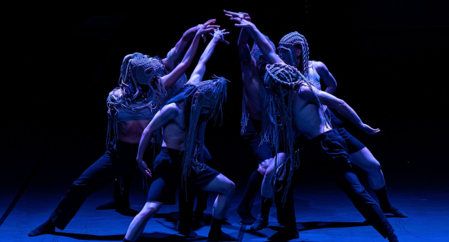 Dansers met maskers in expressieve choreografie