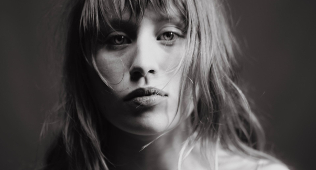 Vrouw in zijdejurk kijkt ernstig in de camera