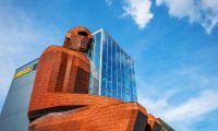 Corpus gebouw met groot zittend mensfiguur en glaswand