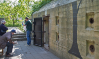 Buitenkant van het Atlantikwall Museum Scheveningen waar mensen luisteren naar de gids