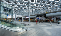 Ingang van een modern treinstation met mensen en roltrappen