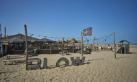 Een strandtent genaamd Blow met parasols en mensen op het strand.