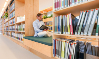 Mann sitzt auf einer Bank in der Bibliothek und liest.
