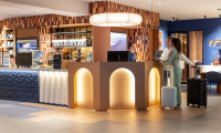 Twee gasten bij de receptie van een modern hotel met koffers.