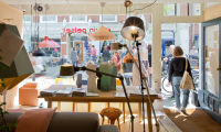 Een blik op een winkelinterieur met lampen en mensen buiten.