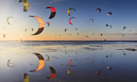 Een lucht vol kites van kitesurfers op het strand van de Zandmotor bij Kijkduin