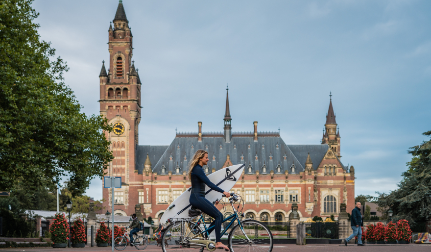 Surfer op de fiets voor het Vredespaleis 