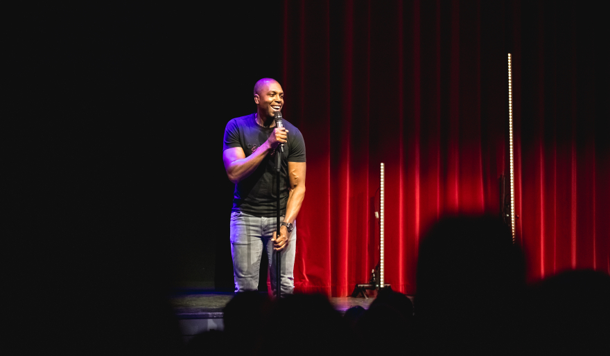Comedian op een podium voor een dicht doek