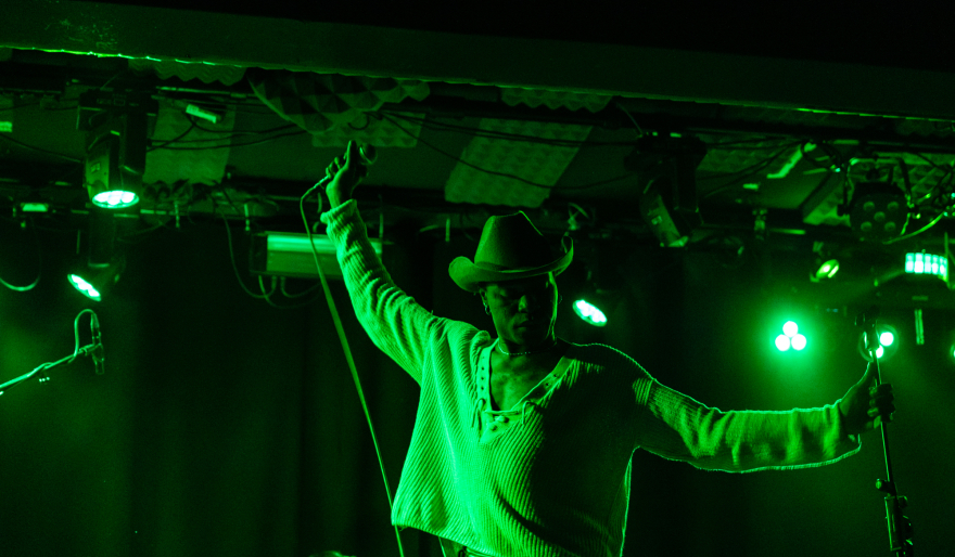 Zanger op podium met cowboyhoed in groen verlichte ruimte