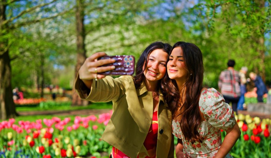 Zwei Freundinnen machen ein Selfie zwischen den Tulpen.