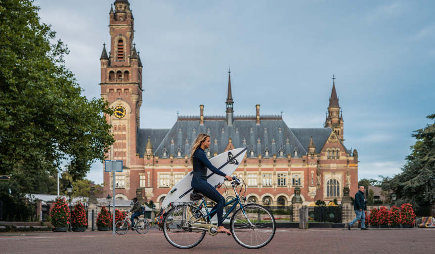 Surfer op de fiets voor het Vredespaleis 