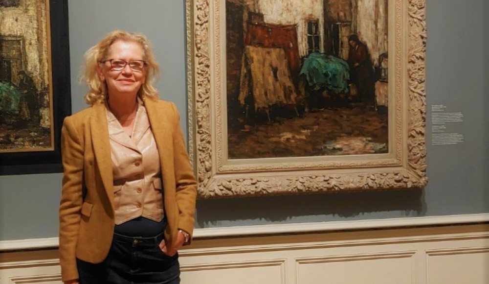 Jeanne van Rutten bij het schilderij Het Witte Huis, een achterplaats in Rotterdam Jeanne van Rutten bij het schilderij Het Witte Huis, een achterplaats in Rotterdam