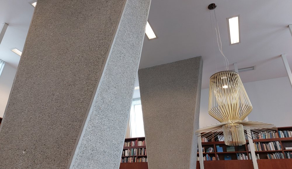 Trapeziumvormige pilaren in de bibliotheek, op de achtergrond de entresol met teakhouten boekenkasten