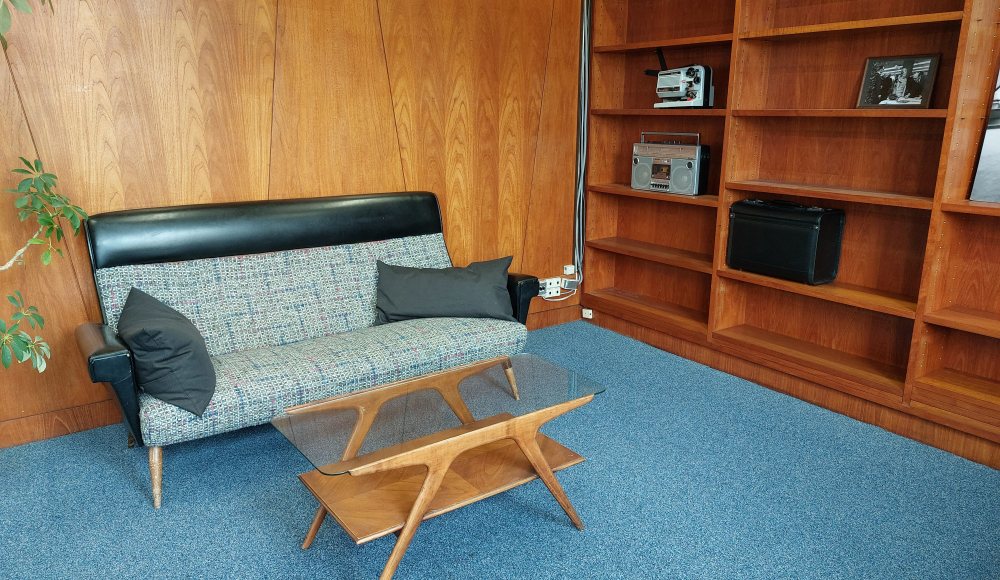 Zithoek in de conferentieruimte met teakhouten  boekenkast en wandbekleding
