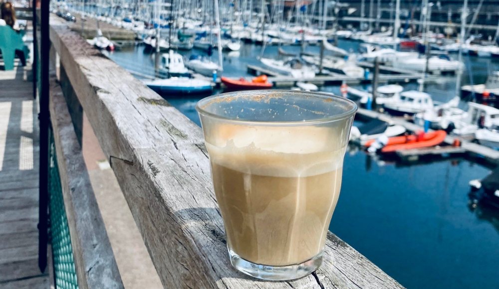 Geniet van een heerlijk kopje koffie op het zonnige terras van Norvolk Scheveningen met zicht op de haven. 