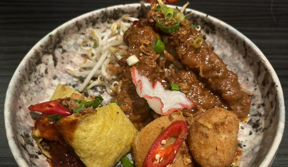 Kleurrijk opgemaakt bord met saté en kleine Indische hapjes