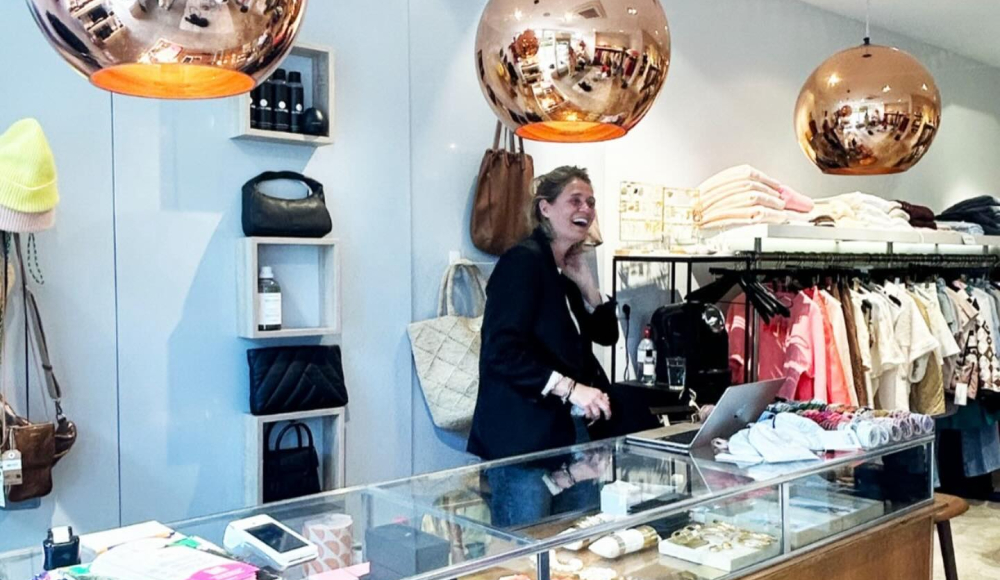 Foto van interieur My Lima Lima. Verkoopster achter houten toonbank met koperen lapmen erboven.