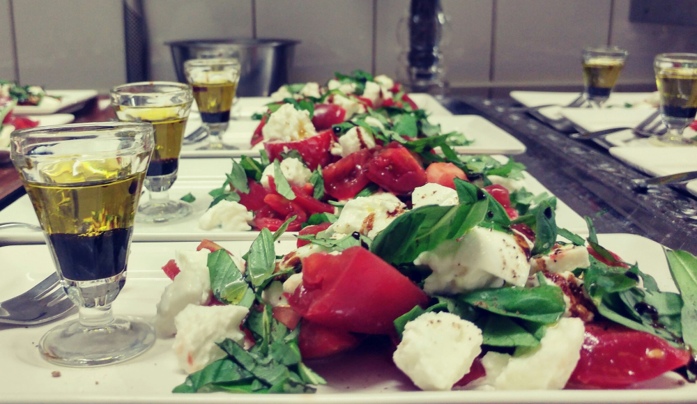 In keuken staan borden op een rij met Caprese salade met glas likeur onderdeel van proeverij Van Kleef.