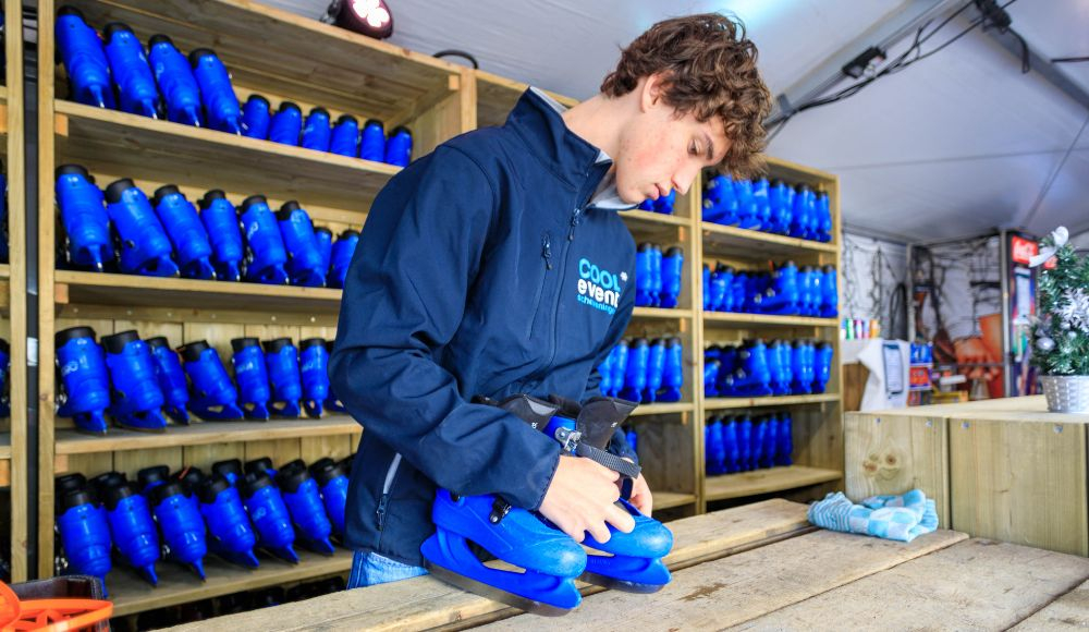 Jongen maakt schaatsen gereed voor gebruik