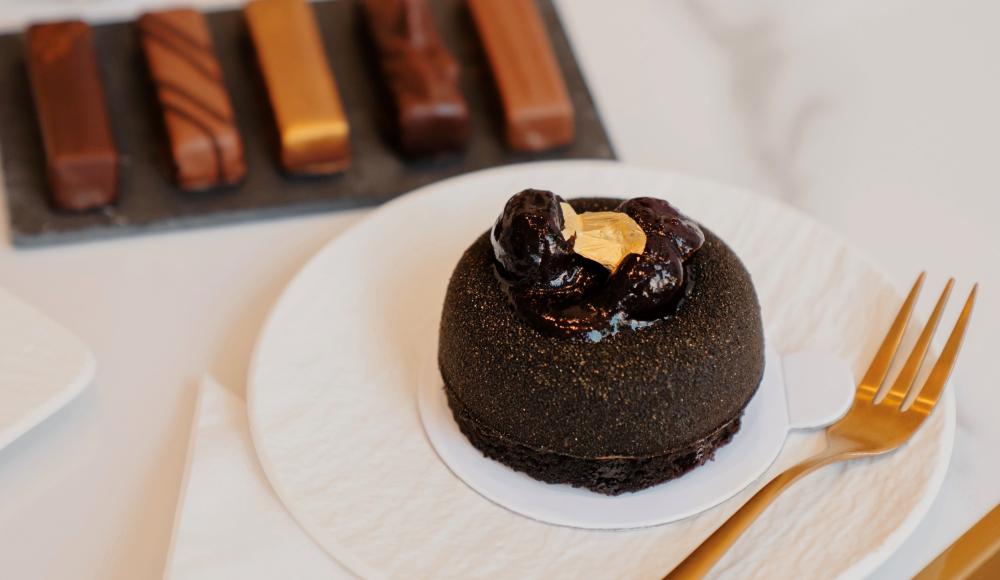 chocoladedessert op een witte schotel met een gouden vork ernaast
