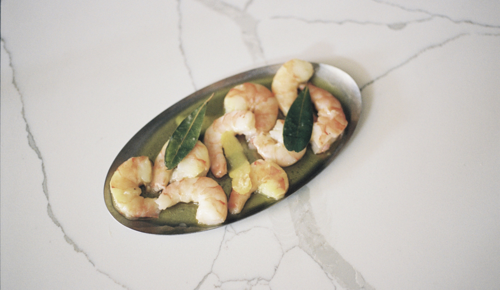 Gamba's sous-vide, citroenrasp, laurier, Griekse olijfolie op een bord