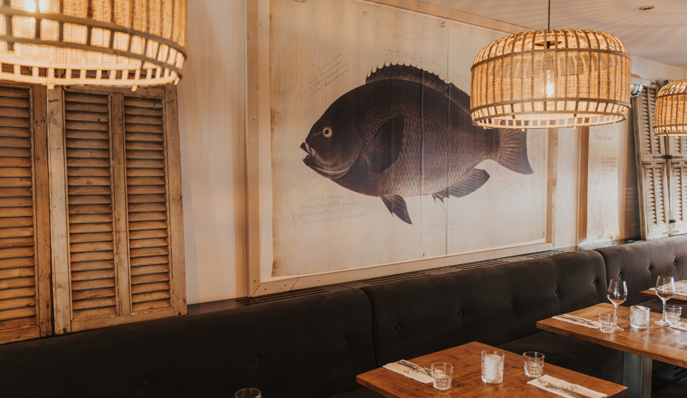 Binnen bij restaurant Vigo Seafoodbar. Rotan lampen en een vissen schilderij. 