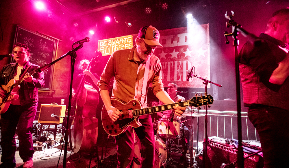Gitarist en band op het podium van de Zwarte Ruiter