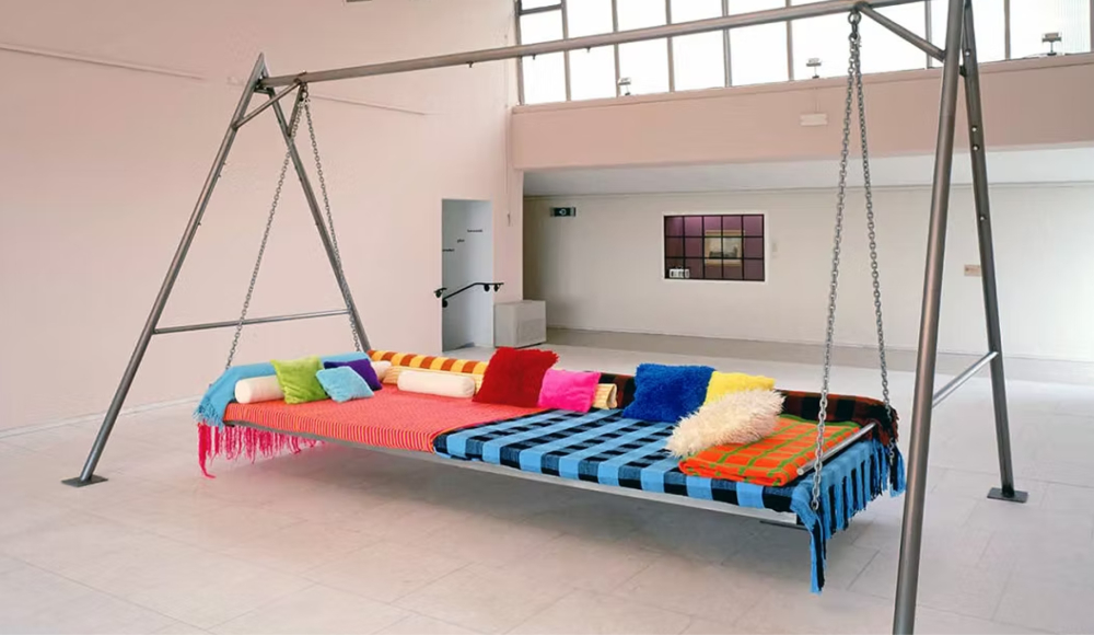 Een groot kunstobject met een schommel en gekleurde bekleding.