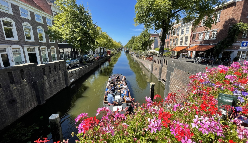 Rondvaart door zonnige gracht met bloemen op brug