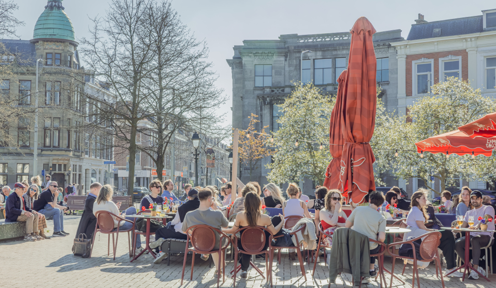Druk terras op een plein in de buitenlucht op het Prins Hendrikplein in Den Haag