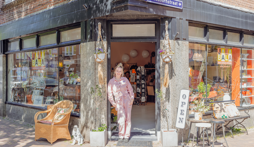 Vrouw voor een winkelpand met vintage meubels op een zonnige dag