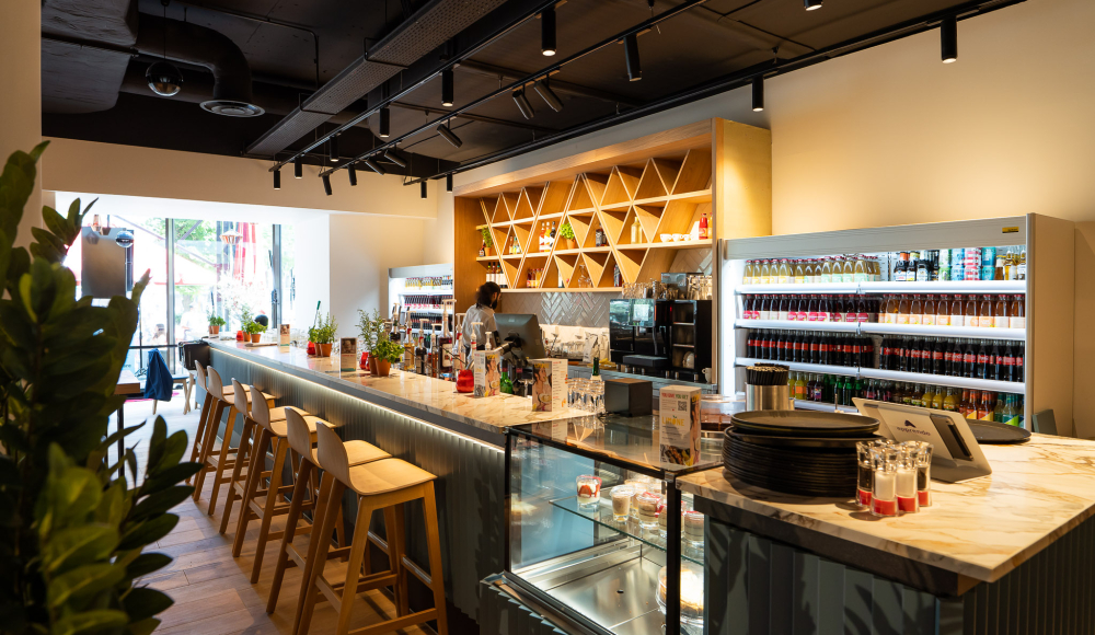 Moderne bar met stijlvolle marmeren toog, een ruime drankselectie en huisgemaakte desserts in de vitrine. Moderne bar met stijlvolle marmeren toog, een ruime drankselectie en huisgemaakte desserts in de vitrine.