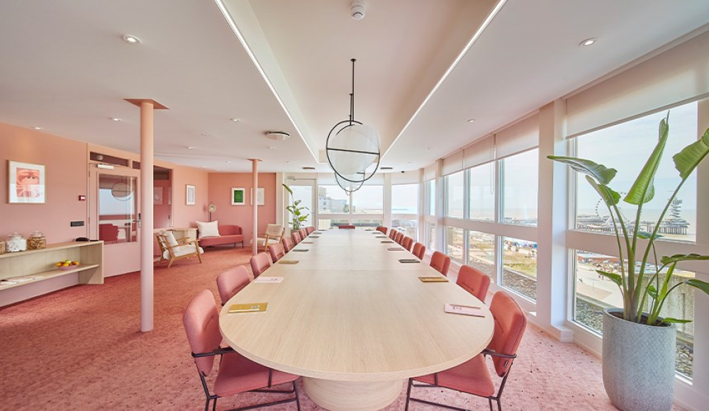 Stijlvolle vergaderruimte met ovale tafel, roze tinten, grote ramen met uitzicht op zee en een moderne, lichte inrichting. Stijlvolle vergaderruimte met ovale tafel, roze tinten, grote ramen met uitzicht op zee en een moderne, lichte inrichting.
