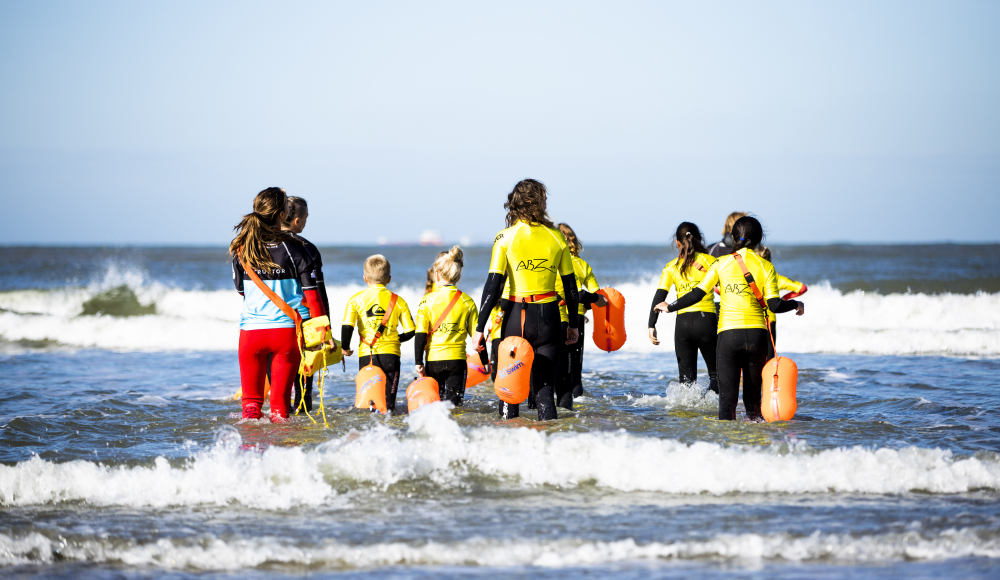Groep kinderen met instructeurs de zee in tijdens een les Groep kinderen met instructeurs de zee in tijdens een les