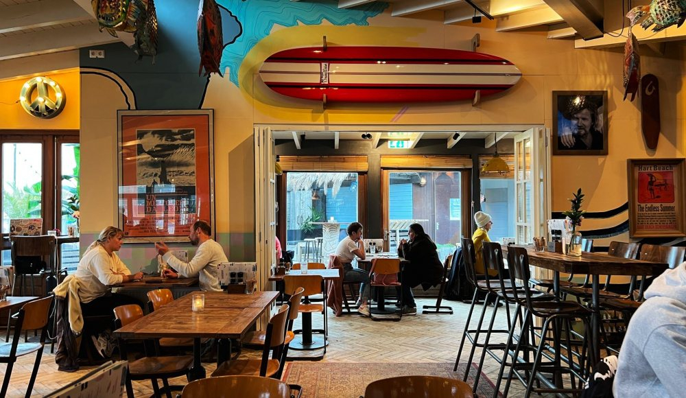 Het sfeervolle surfrestaurant van Hart Beach met houten tafels, kleurrijke surfdecoratie en relaxte vibe. Het sfeervolle surfrestaurant van Hart Beach met houten tafels, kleurrijke surfdecoratie en relaxte vibe.