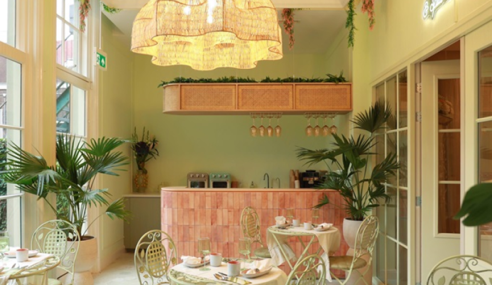 Sfeervol high tea café met zachte groene muren, een roze tegelbar, rieten lampen en weelderige planten voor een tropische, stijlvolle uitstraling Sfeervol high tea café met zachte groene muren, een roze tegelbar, rieten lampen en weelderige planten voor een tropische, stijlvolle uitstraling