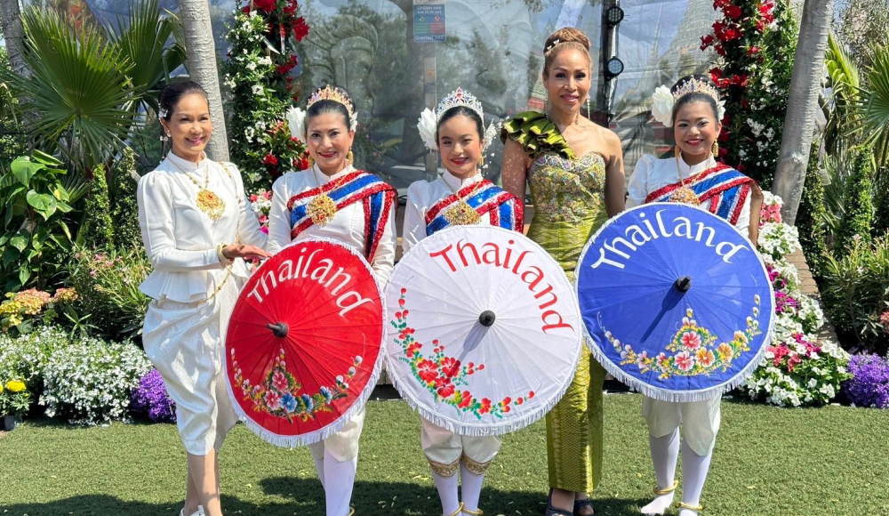 Poserende dames in traditionele Thaise kleding met papieren parasolletjes naar voren gericht Poserende dames in traditionele Thaise kleding met papieren parasolletjes naar voren gericht